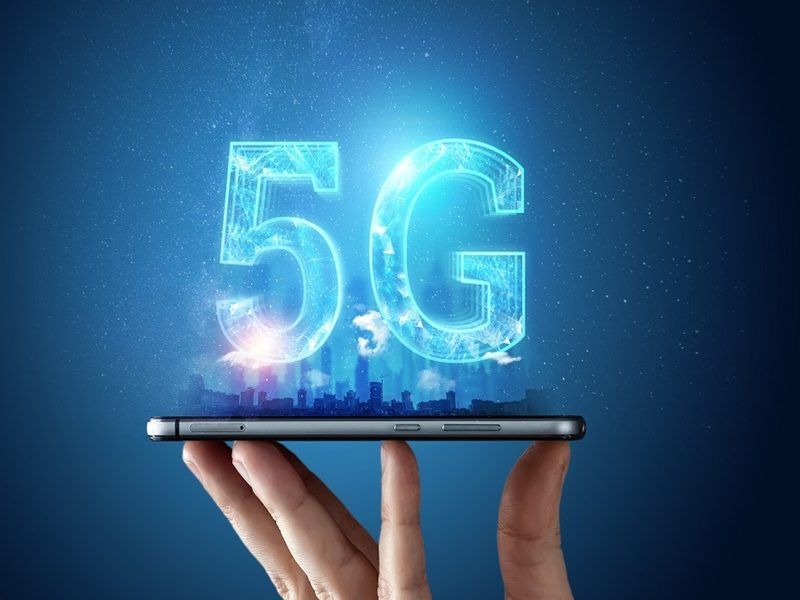 Smartphone affichant la technologie 5G avec ville en arrière-plan, illustrant la performance du réseau 5G comparé au 4G au Canada.